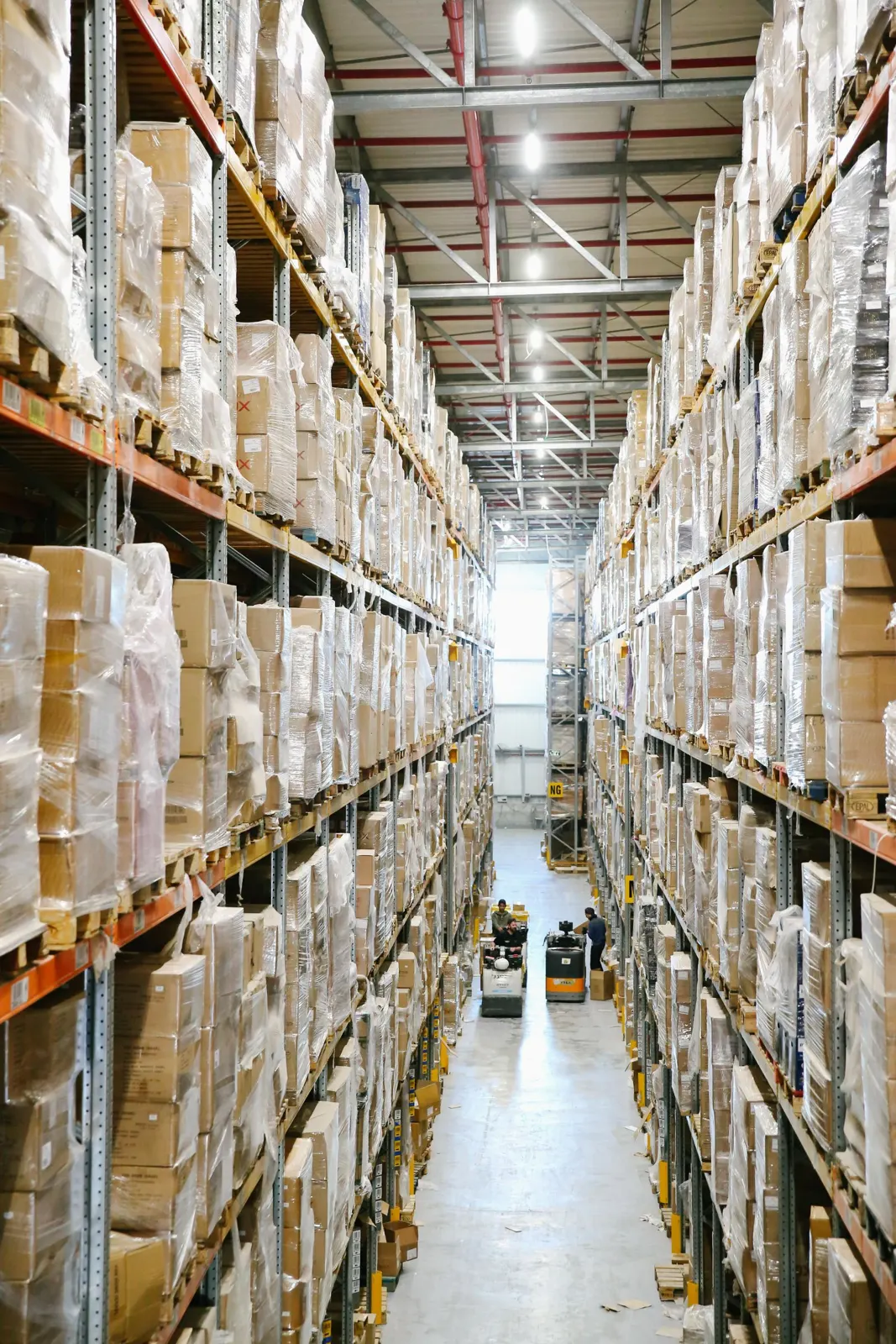 Two warehouse aisles with high shelving stacked with wrapped cardboard boxes